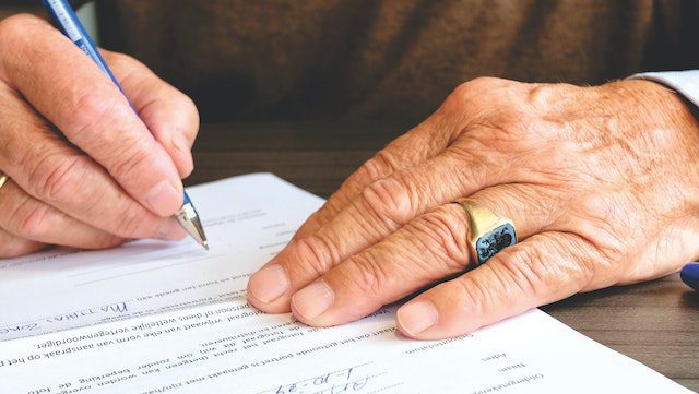 an old man signing legal papers 