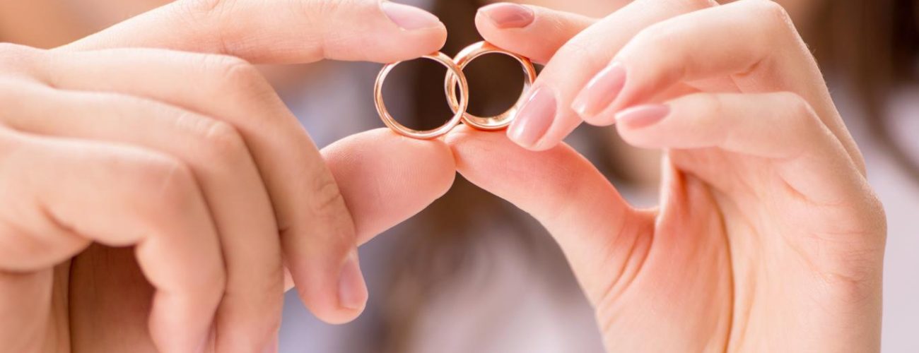 Two hands gently hold a pair of golden wedding bands, a central symbol of unity and commitment in a civil marriage, with the focus on the interlocking rings highlighting the cherished bond of matrimony.