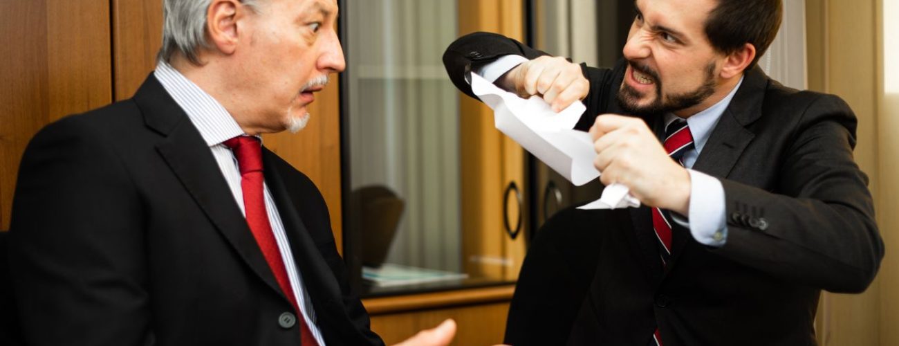 A businessman angrily tearing a contract in half in front of another individual. The shocked expression of the other person signifies a heated argument over a breach of contract.