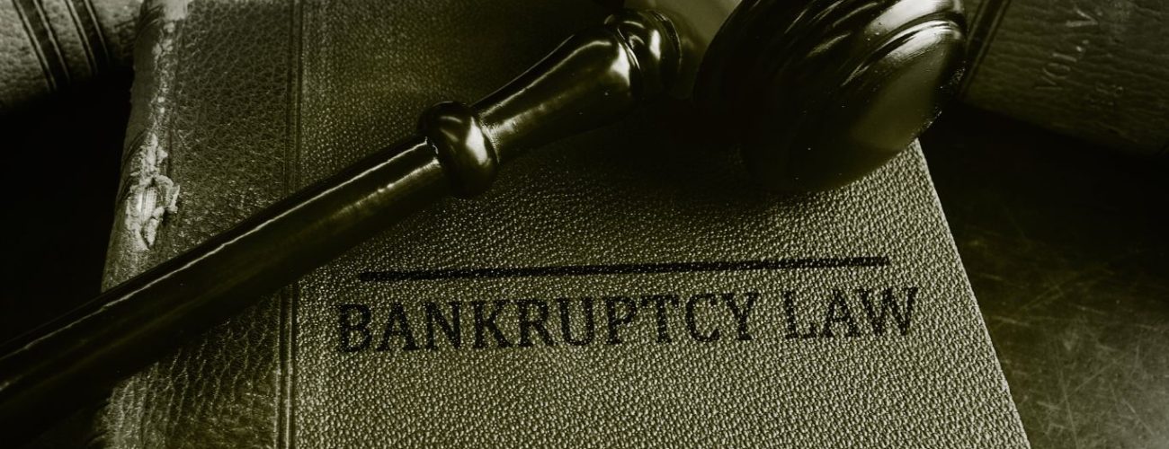 A judge's gavel resting on an old, textured book titled 'Bankruptcy Law', symbolizing legal authority and procedures related to bankruptcy."