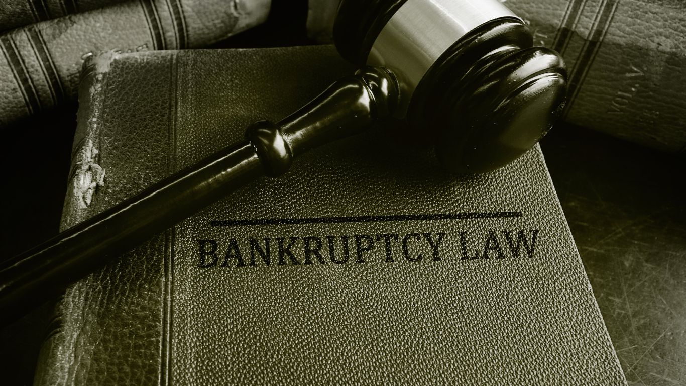 A judge's gavel resting on an old, textured book titled 'Bankruptcy Law', symbolizing legal authority and procedures related to bankruptcy."