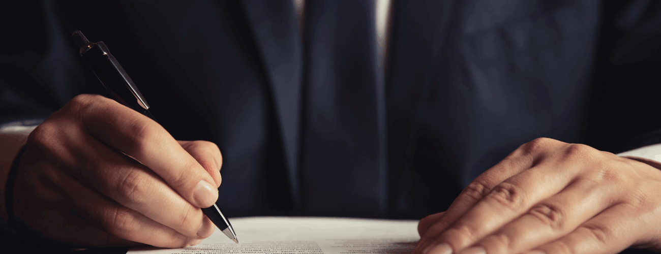 Professional businessman signing legal contract document with pen in formal business setting