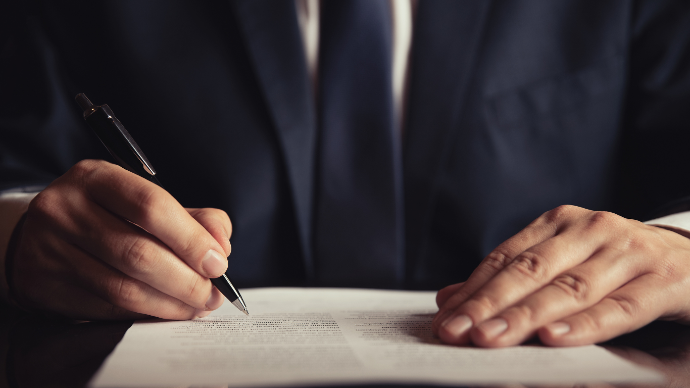 Professional businessman signing legal contract document with pen in formal business setting